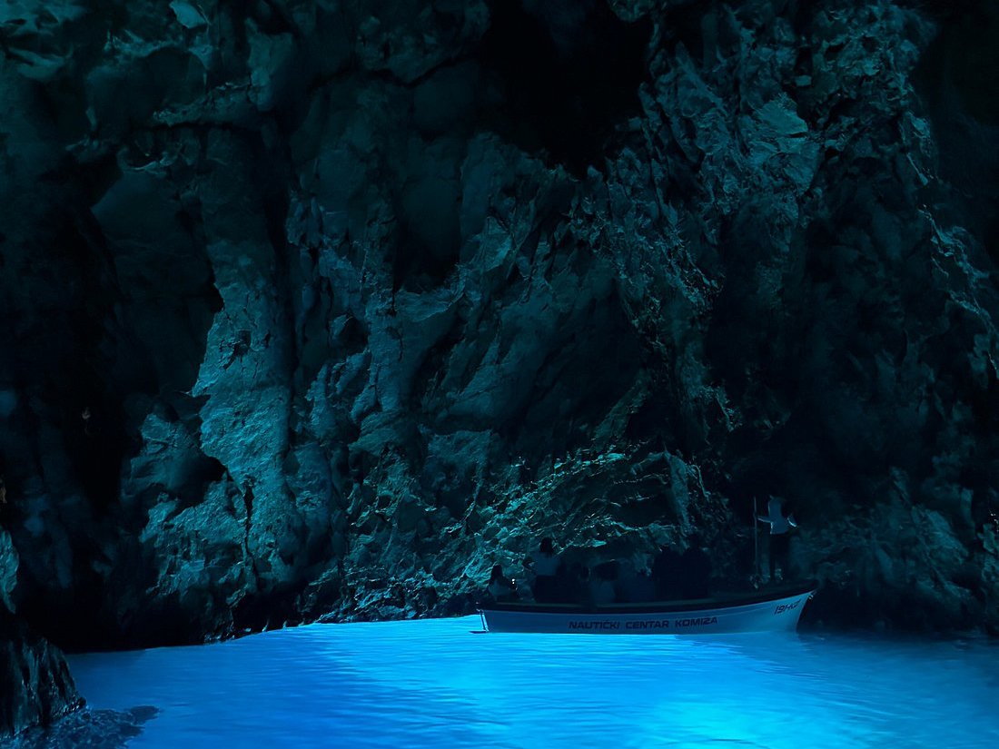 Komiža boat on luminous blue water deep inside the Blue Cave on Biševo
