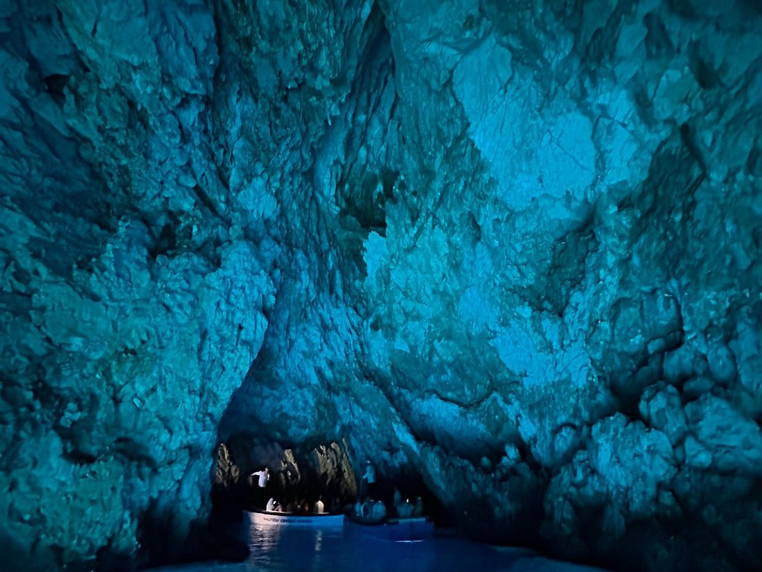 Overhead view of small boats inside the glowing Blue Cave on Biševo