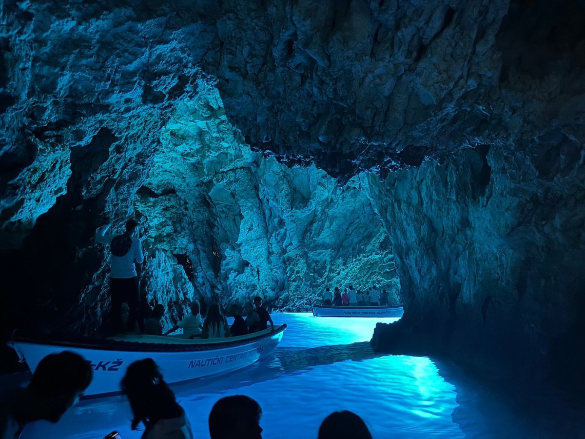 Tourist boats floating on glowing blue water inside the Blue Cave on Biševo