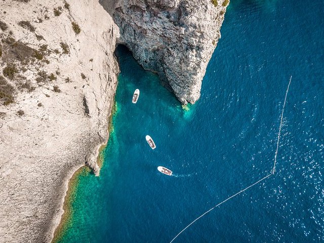 Aerial view of white cliffs and turquoise cove with small tour boats