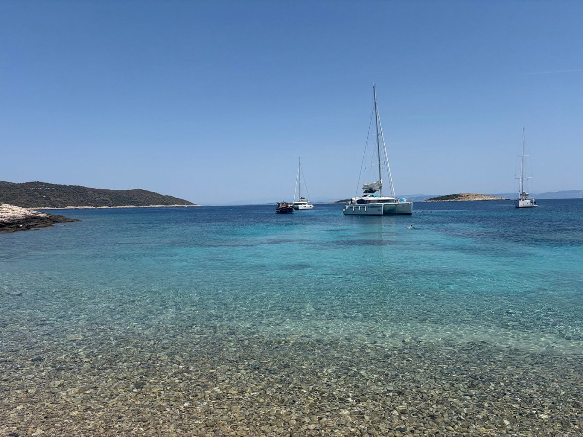 Catamaran and sailboats anchored in a clear turquoise bay