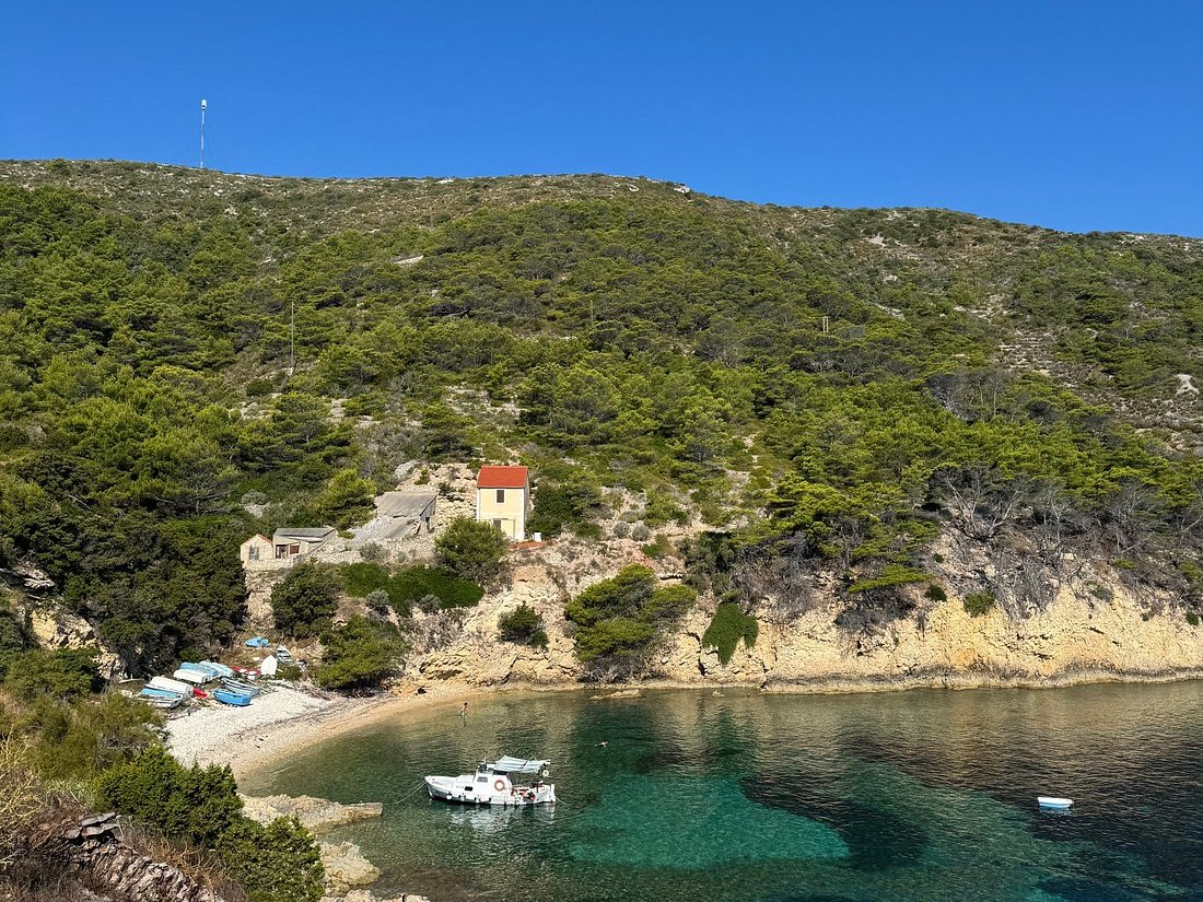 Hillside cove with turquoise water and a stone house with a red roof
