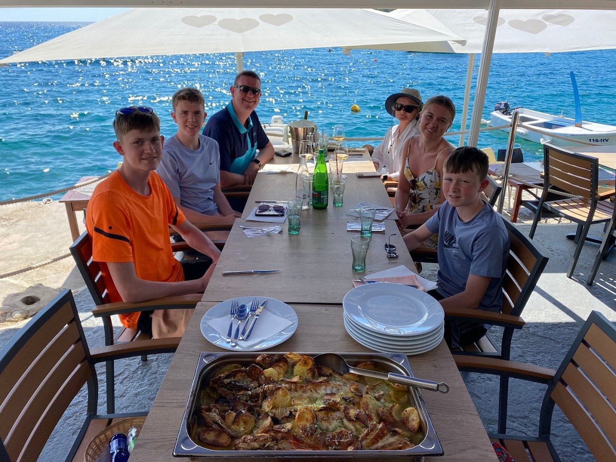 Family seaside lunch with roasted fish and potatoes in Milna