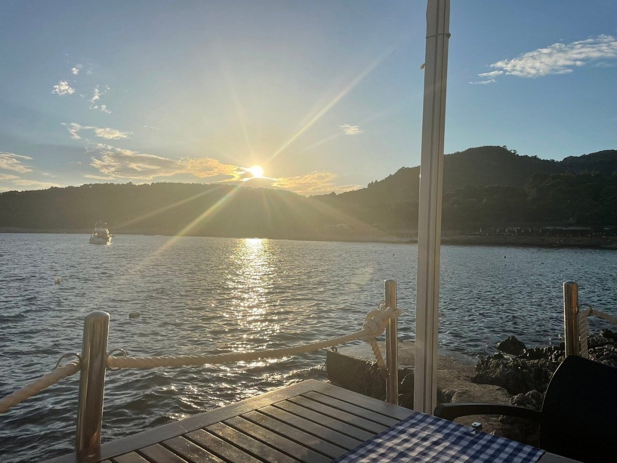 Wooden terrace table set for lunch with sunset sea view in Milna