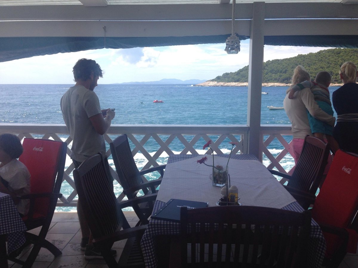 Terrace table overlooking turquoise sea and green hills near Milna